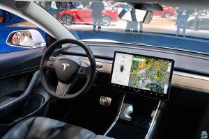 Tesla Model 3 compact full electric car interior with a large touch screen on the dashboard.