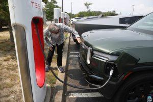 Rivian SUV charging at a Tesla Supercharger.