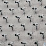 a pattern of CCTV surveillance cameras on a wall, all pointing in different directions.