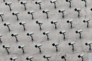a pattern of CCTV surveillance cameras on a wall, all pointing in different directions.