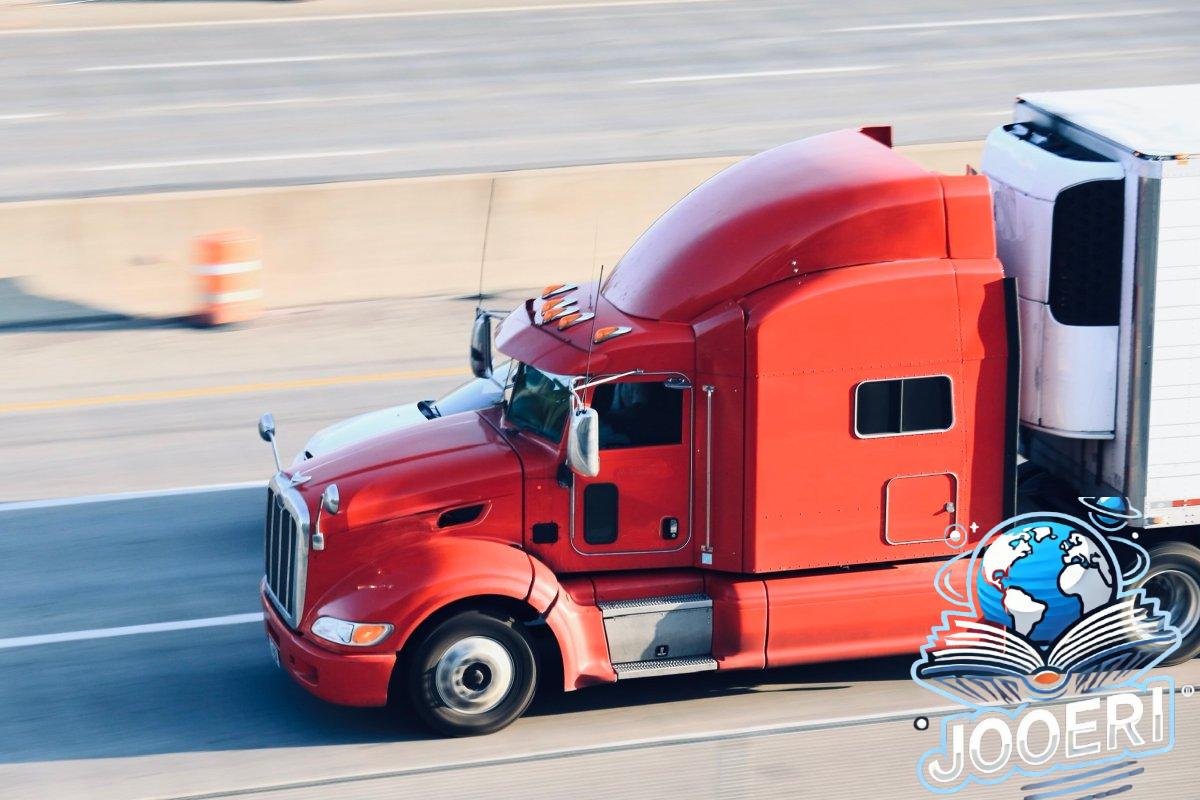 A red semi towing a trailer drives down a highway.