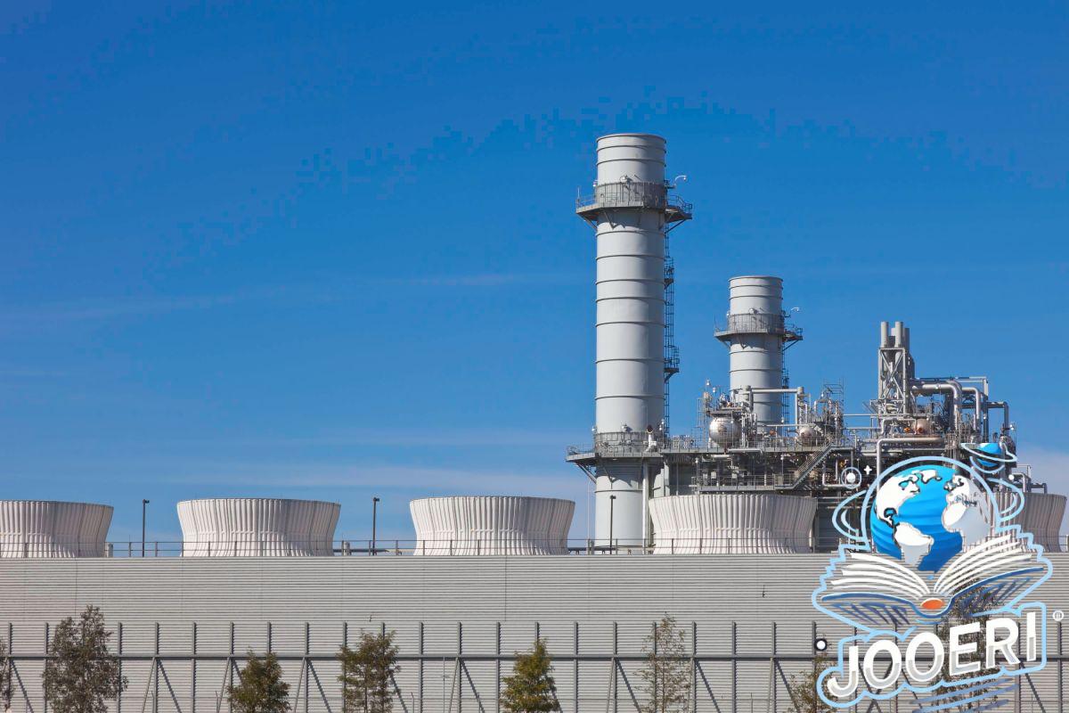 Smoke stacks from a natural gas power plant stand against a blue sky.