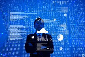 Man standing in front of big blue screen with charts and data spread out before him.