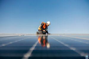 A handyman on the rooftop installing solar panels.