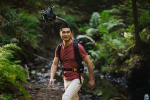 Man hiking in a forest wearing Odyssey camera pack